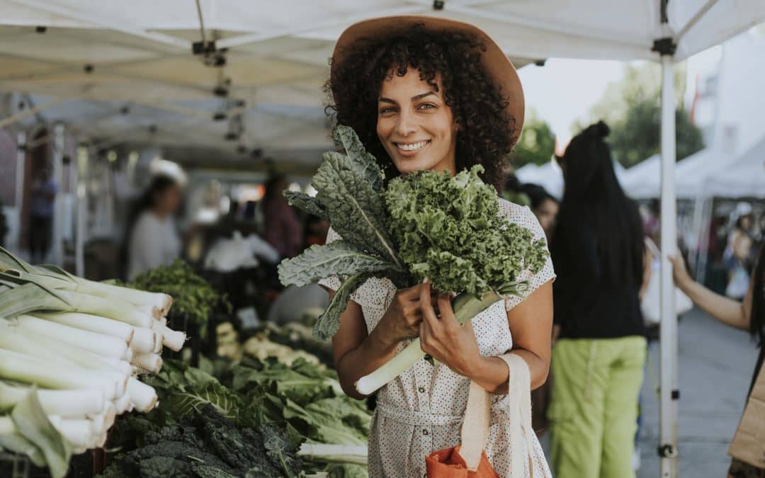 Beautiful woman buying kale at a farmers market