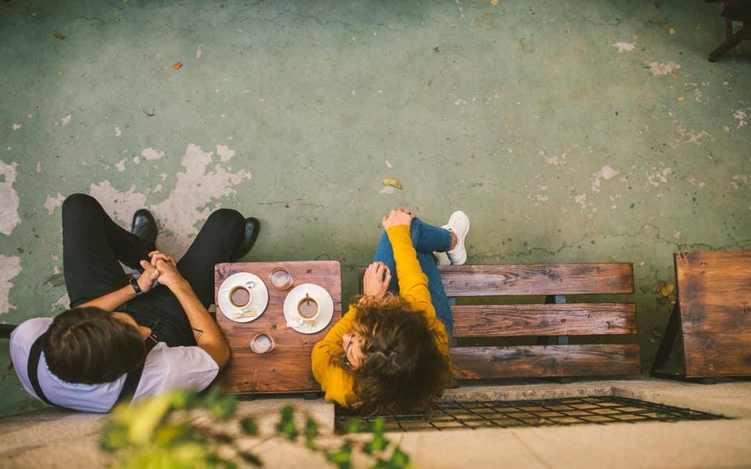 couple sitting on bench drinking coffee